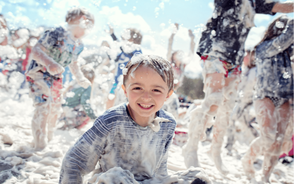 A young child among other children in a foam dance party.