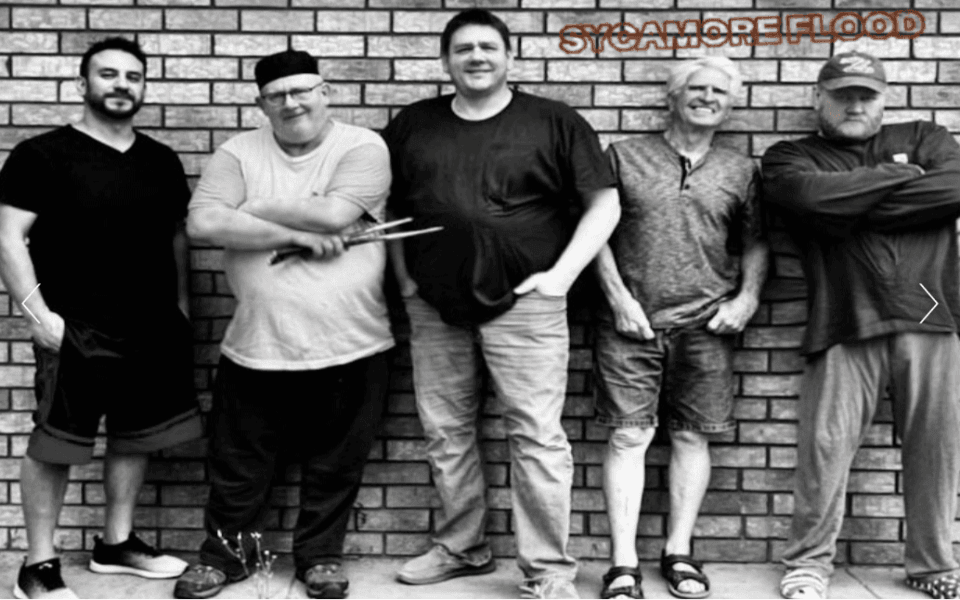 Sycamore Flood members in front of a brick wall and pictured in black and white color scale.